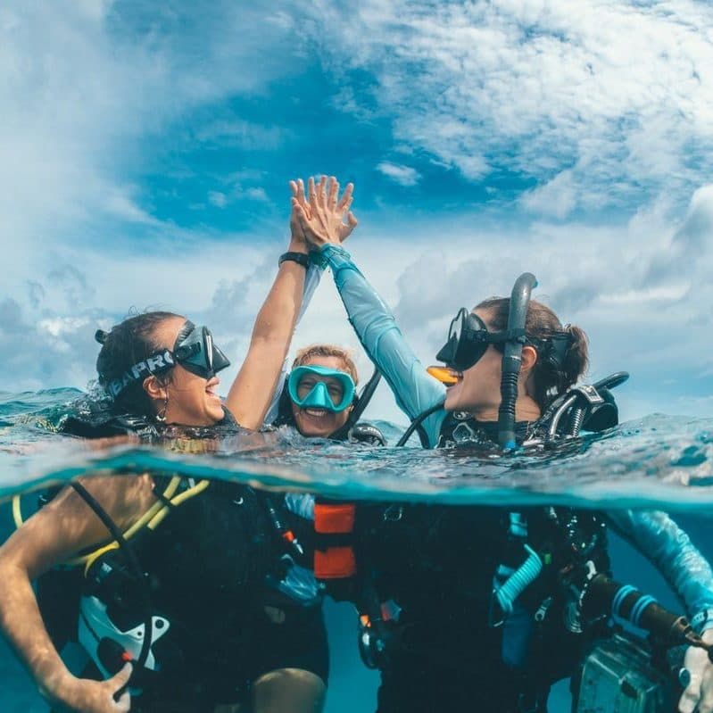 Friends high-fiving at the surface after a dive