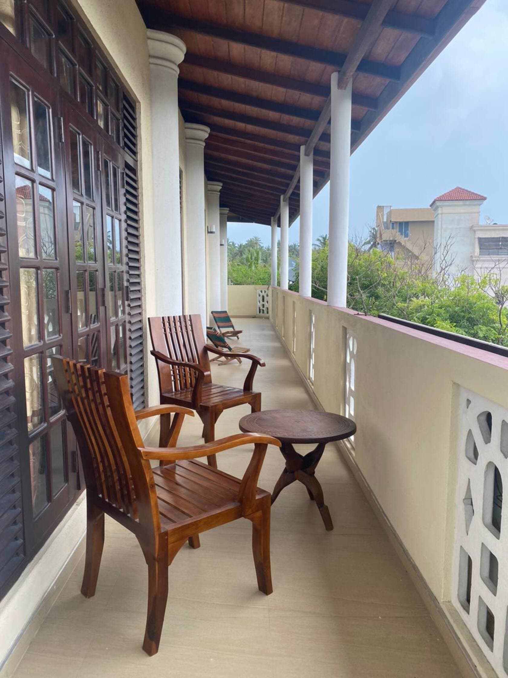 Balcony of the Seahorse Dreams apartment with wooden armchairs and a view over the treetops